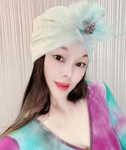 A mint blue, shimmering headscarf adorned with feathers